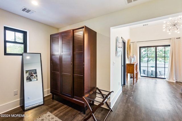 hallway featuring a notable chandelier, a healthy amount of sunlight, and dark wood-type flooring