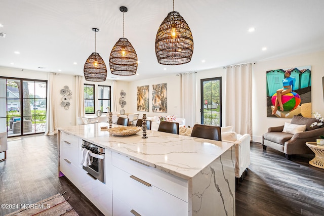 kitchen with pendant lighting, a wealth of natural light, a center island, and white cabinets