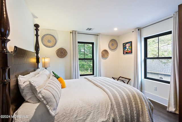 bedroom with multiple windows and dark wood-type flooring