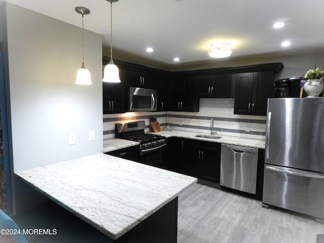 kitchen featuring sink, kitchen peninsula, appliances with stainless steel finishes, light hardwood / wood-style flooring, and decorative backsplash