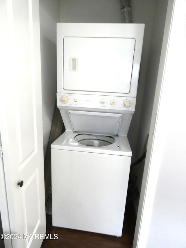 clothes washing area with dark hardwood / wood-style flooring and stacked washer / drying machine