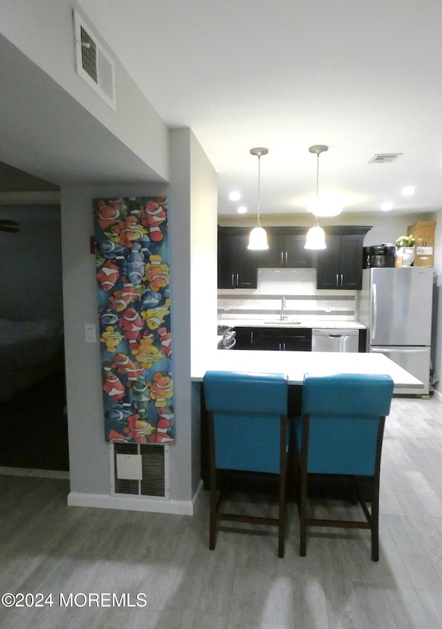 kitchen with hardwood / wood-style flooring, sink, kitchen peninsula, appliances with stainless steel finishes, and pendant lighting