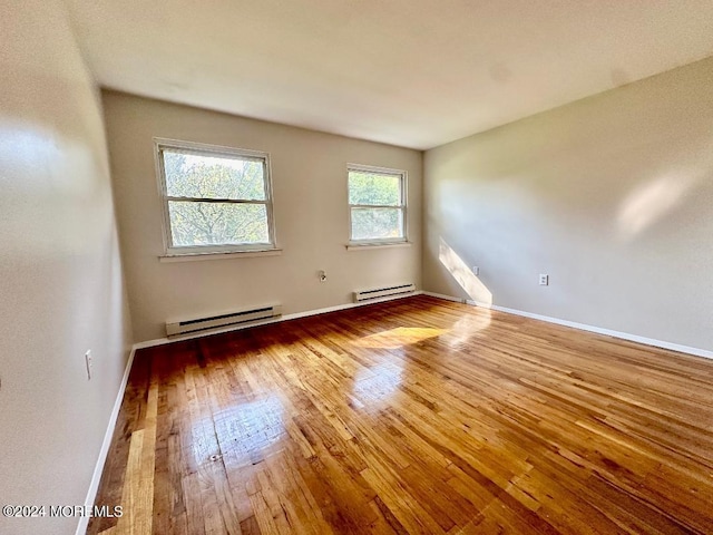 unfurnished room featuring baseboard heating and hardwood / wood-style flooring