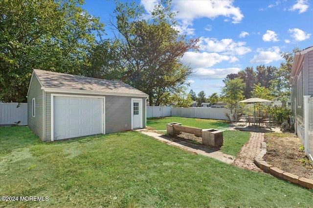 view of yard featuring a garage, a patio, and an outdoor structure