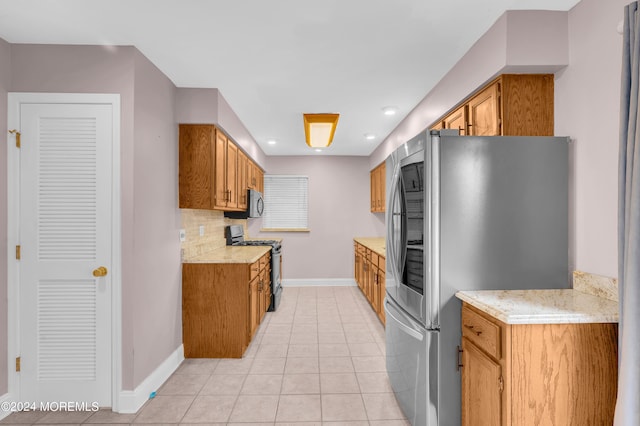 kitchen featuring tasteful backsplash, stainless steel appliances, light stone counters, and light tile patterned floors