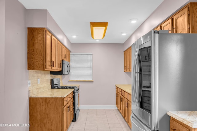 kitchen featuring tasteful backsplash, light tile patterned flooring, light stone countertops, and appliances with stainless steel finishes