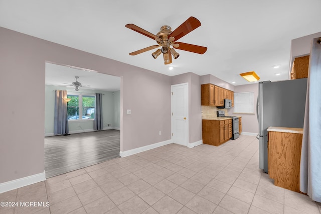 kitchen featuring light tile patterned flooring, ceiling fan, appliances with stainless steel finishes, and decorative backsplash