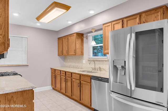 kitchen featuring sink, light tile patterned floors, backsplash, stainless steel appliances, and light stone countertops