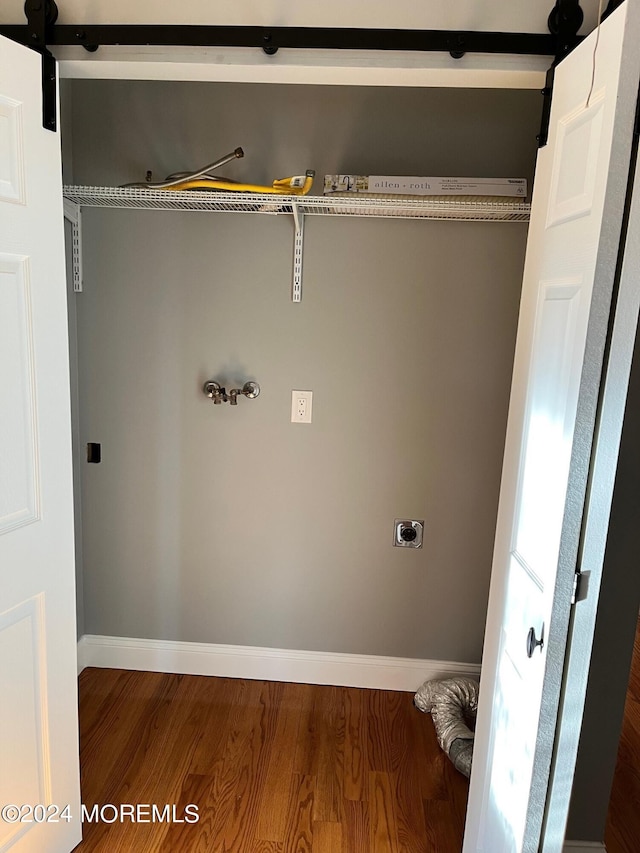 laundry room featuring laundry area, a barn door, electric dryer hookup, and wood finished floors