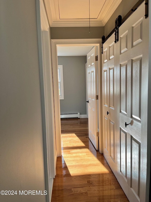 corridor featuring a baseboard heating unit, attic access, ornamental molding, and wood finished floors