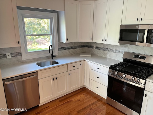 kitchen with white cabinets, sink, stainless steel appliances, dark hardwood / wood-style flooring, and decorative backsplash