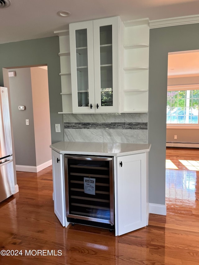 bar featuring wine cooler, a baseboard heating unit, freestanding refrigerator, a dry bar, and tasteful backsplash