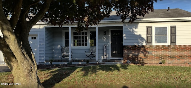 view of front of home featuring covered porch, brick siding, and a front yard