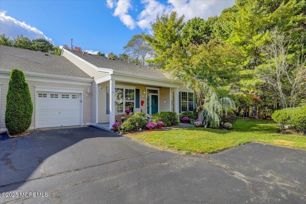 view of front of property with a front lawn, covered porch, and a garage