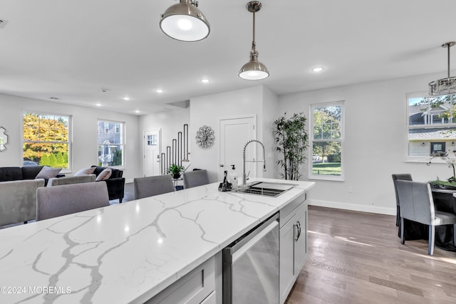 kitchen featuring sink, hanging light fixtures, light hardwood / wood-style floors, light stone counters, and white cabinetry