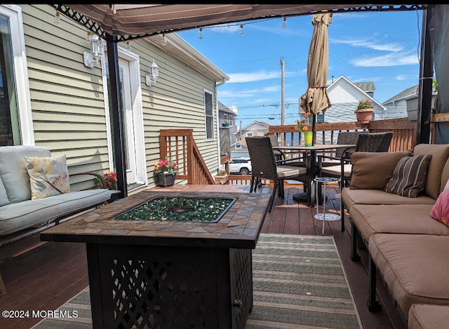 wooden deck featuring an outdoor living space with a fire pit