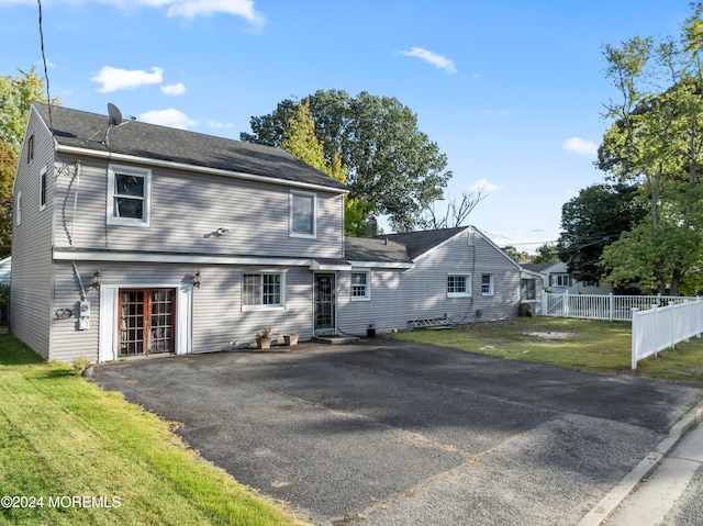 colonial house with a front yard, fence, driveway, and an attached garage