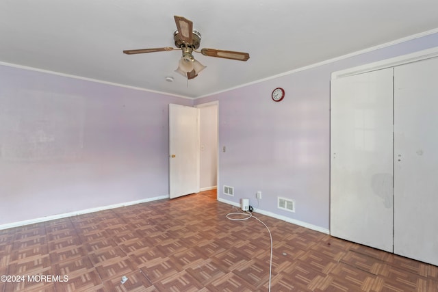 unfurnished bedroom with dark parquet flooring, crown molding, a closet, and ceiling fan