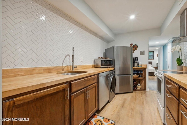 kitchen with wooden counters, sink, appliances with stainless steel finishes, and light hardwood / wood-style flooring