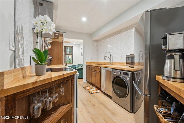 kitchen featuring dishwasher, butcher block counters, light wood-type flooring, and washer / clothes dryer