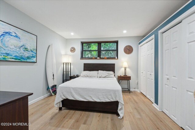 bedroom featuring multiple closets and light hardwood / wood-style flooring