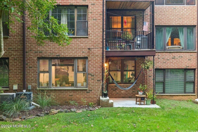 back of property with central AC, a yard, and a balcony