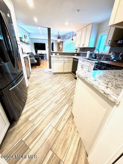 kitchen with white cabinetry, black appliances, light hardwood / wood-style flooring, and kitchen peninsula