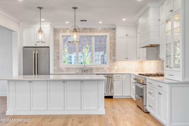 kitchen with stainless steel appliances, a kitchen island, light countertops, a sink, and white cabinets