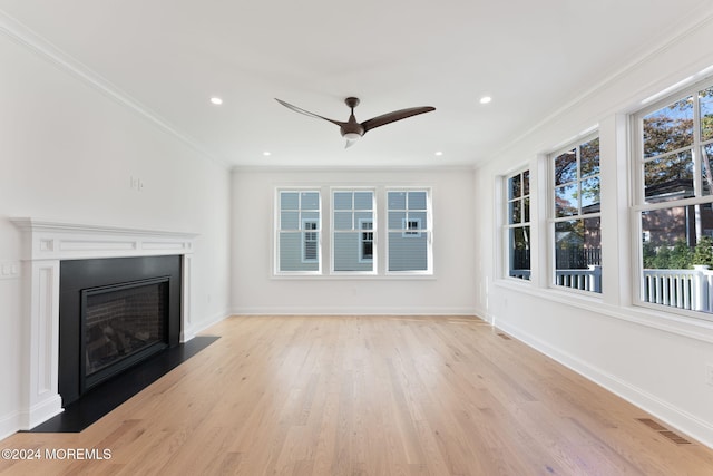 unfurnished living room with a ceiling fan, light wood-style flooring, baseboards, ornamental molding, and a fireplace with flush hearth