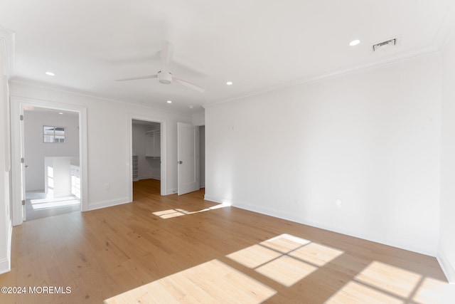 unfurnished bedroom with crown molding, a walk in closet, baseboards, light wood-style floors, and recessed lighting