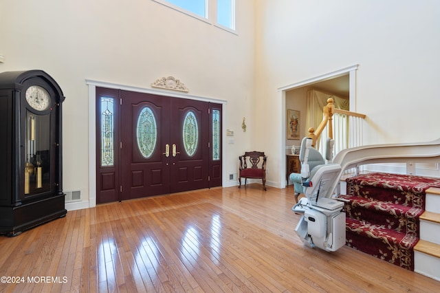 entrance foyer with light hardwood / wood-style flooring and a towering ceiling