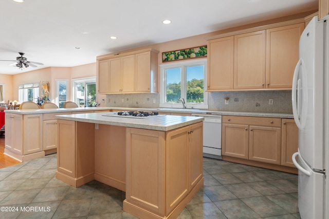 kitchen featuring a healthy amount of sunlight, white appliances, ceiling fan, and a kitchen island