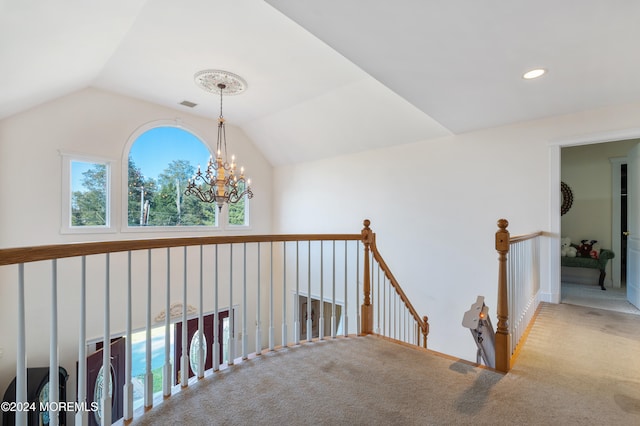 hall with carpet, vaulted ceiling, and an inviting chandelier