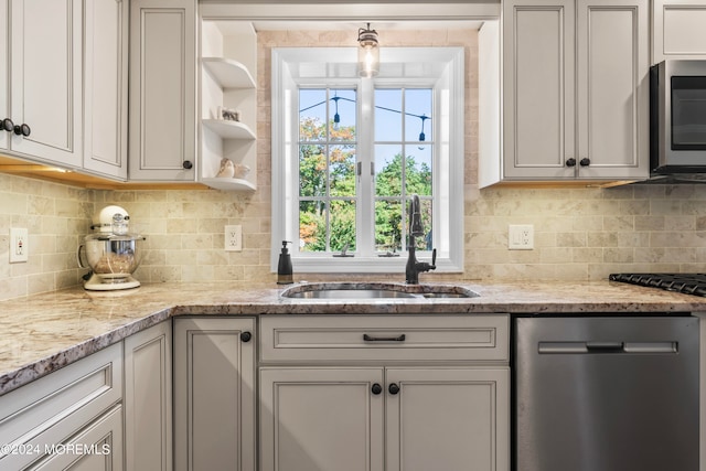 kitchen with decorative backsplash, stainless steel appliances, sink, and light stone counters