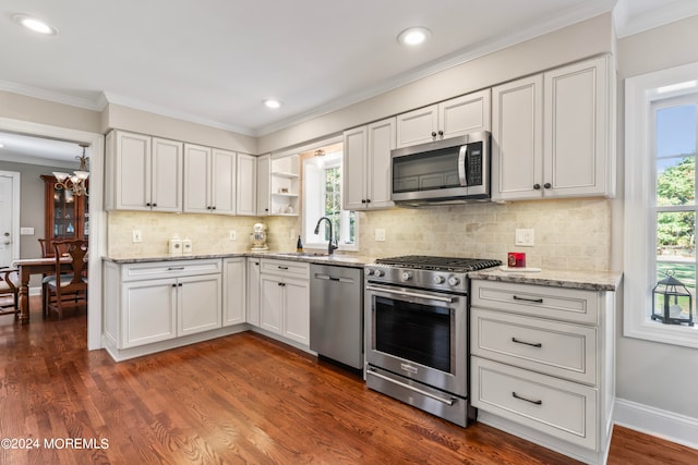 kitchen with dark wood-type flooring, ornamental molding, sink, white cabinets, and appliances with stainless steel finishes