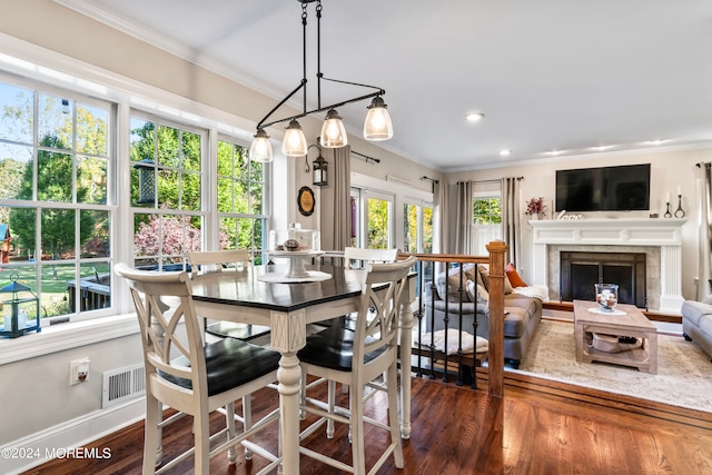 dining space featuring dark hardwood / wood-style floors, ornamental molding, a wealth of natural light, and a fireplace