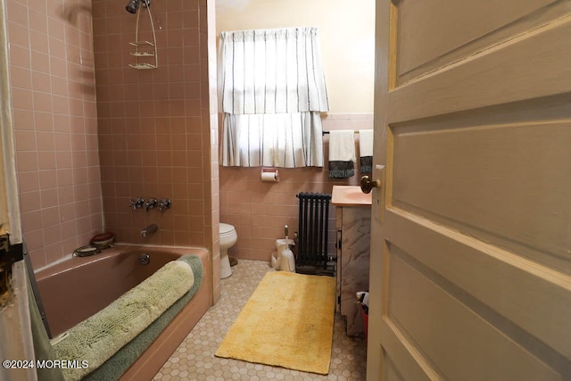 bathroom with toilet, tile walls, radiator heating unit, and tiled shower / bath