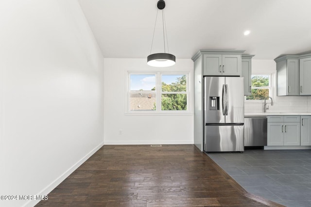 kitchen featuring appliances with stainless steel finishes, dark hardwood / wood-style floors, tasteful backsplash, and gray cabinets