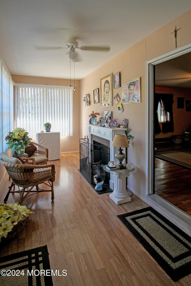 living room with a brick fireplace, light wood-type flooring, and ceiling fan