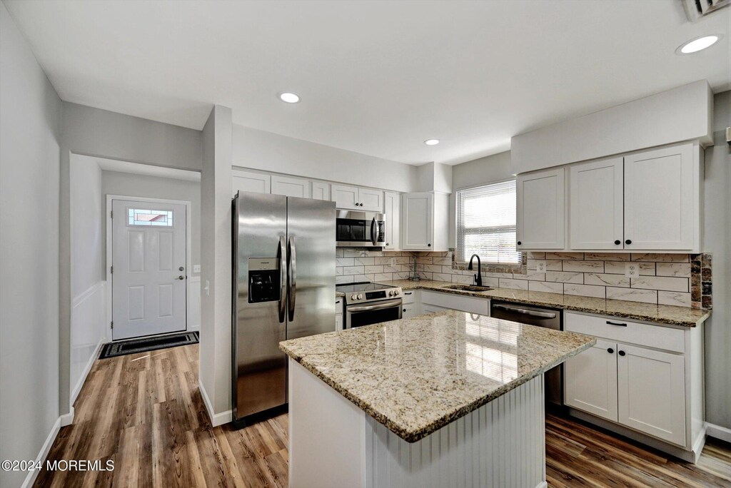 kitchen featuring dark hardwood / wood-style flooring, white cabinets, sink, a kitchen island, and appliances with stainless steel finishes