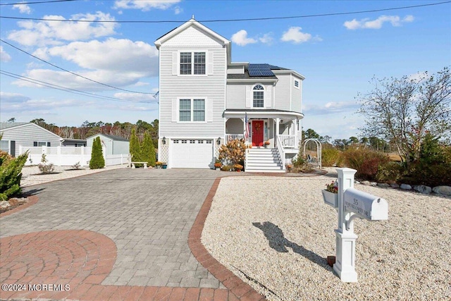 front of property with covered porch, solar panels, and a garage