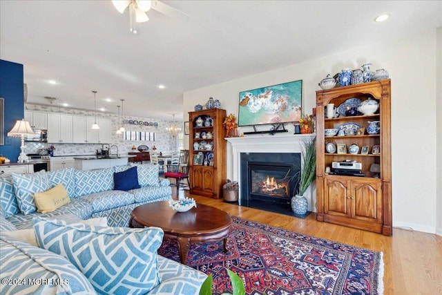 living room featuring sink, light hardwood / wood-style flooring, and ceiling fan