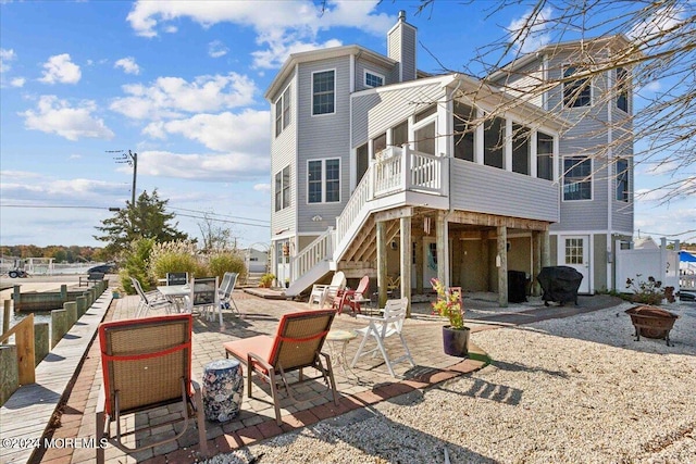 rear view of property featuring a patio area, a sunroom, and an outdoor fire pit