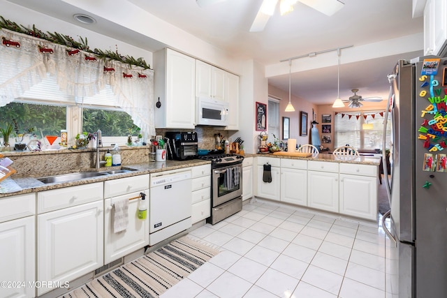 kitchen with white cabinets, hanging light fixtures, backsplash, appliances with stainless steel finishes, and sink