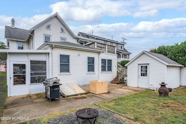 rear view of property featuring a storage shed and a fire pit