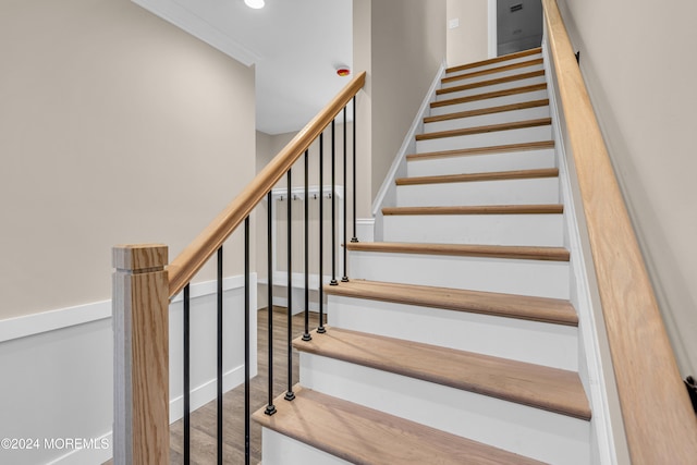 stairs featuring hardwood / wood-style floors and ornamental molding