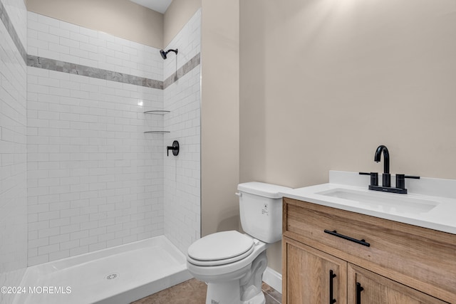 bathroom with tiled shower, tile patterned floors, vanity, and toilet