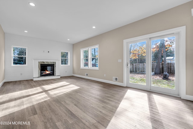 unfurnished living room with a high end fireplace and light wood-type flooring