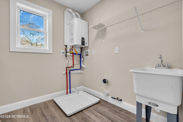 laundry area featuring sink, tankless water heater, gas dryer hookup, hookup for a washing machine, and hardwood / wood-style floors