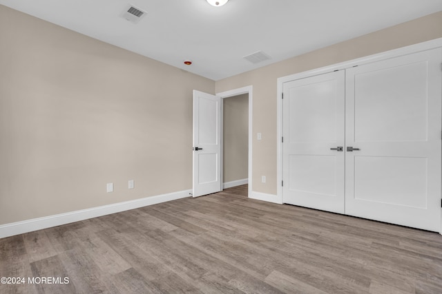 unfurnished bedroom with light hardwood / wood-style floors and a closet